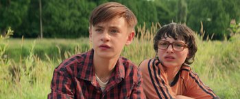 Movie still from “It” (2017), directed by Andy Muschietti – Two young men sitting next to each other in a field; Close Up shot, Low angle