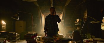 Movie still from “It Chapter Two” (2019), directed by Andy Muschietti – A man standing in front of a pile of books on the phone; Medium shot, Low angle