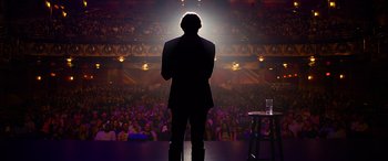 Movie still from “It Chapter Two” (2019), directed by Andy Muschietti – A man standing in front of an audience on a stage; Wide shot, Low angle