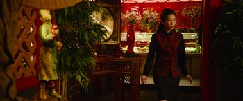 Movie still from “It Chapter Two” (2019), directed by Andy Muschietti – A woman in a red and black outfit walking in a room; Medium shot, Over the shoulder angle