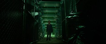 Movie still from “It Chapter Two” (2019), directed by Andy Muschietti – A man standing in a dark room in front of a metal fence; Wide shot, Low angle