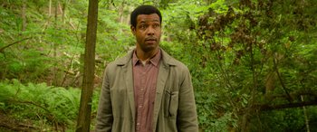 Movie still from “It Chapter Two” (2019), directed by Andy Muschietti – A man standing in the woods looking at the camera; Medium shot, Over the shoulder angle