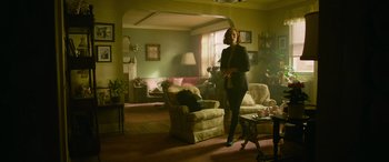 Movie still from “It Chapter Two” (2019), directed by Andy Muschietti – A woman standing in a living room next to a couch; Wide shot, Low angle