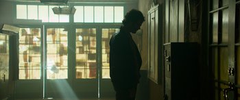 Movie still from “It Chapter Two” (2019), directed by Andy Muschietti – A man standing in a dark room with his head turned to the side; Wide shot, Low angle