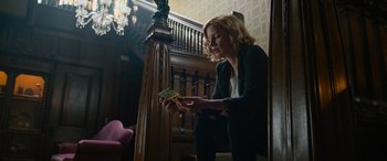 Movie still from “It Chapter Two” (2019), directed by Andy Muschietti – A woman sitting on the stairs looking at a piece of paper; Medium shot, Low angle
