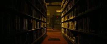 Movie still from “It Chapter Two” (2019), directed by Andy Muschietti – A man standing in a room with a bunch of bookshelves; Wide shot, Low angle