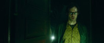 Movie still from “It Chapter Two” (2019), directed by Andy Muschietti – A man standing in a dark room holding a flashlight; Medium shot, Low angle