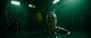 Movie still from “It Chapter Two” (2019), directed by Andy Muschietti – A man standing in front of a person wearing a yellow raincoat; Medium shot, Low angle