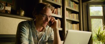 Movie still from “It Chapter Two” (2019), directed by Andy Muschietti – A man sitting in front of a computer talking on a cell phone; Close Up shot, Low angle