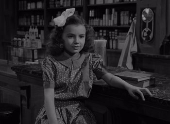 Movie still from “It's a Wonderful Life” (1946), directed by Frank Capra – A young girl sitting at a counter in a store; Medium shot, High angle