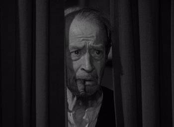 Movie still from “It's a Wonderful Life” (1946), directed by Frank Capra – An old man smoking a cigarette while looking out a window; Close Up shot, Low angle