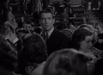 Movie still from “It's a Wonderful Life” (1946), directed by Frank Capra – A black and white photo of a man in a crowd of people; Medium shot, Over the shoulder angle