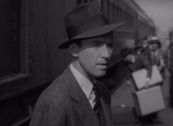 Movie still from “It's a Wonderful Life” (1946), directed by Frank Capra – A man wearing a suit and a hat standing in front of a train; Close Up shot, Low angle
