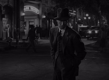 Movie still from “It's a Wonderful Life” (1946), directed by Frank Capra – A black and white photo of a man in a suit and hat; Medium shot, Low angle