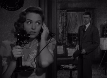 Movie still from “It's a Wonderful Life” (1946), directed by Frank Capra – A woman talking on a phone while a man watches; Medium shot, High angle