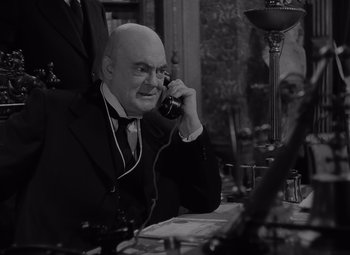 Movie still from “It's a Wonderful Life” (1946), directed by Frank Capra – An older man sitting at a table talking on a phone; Close Up shot, High angle