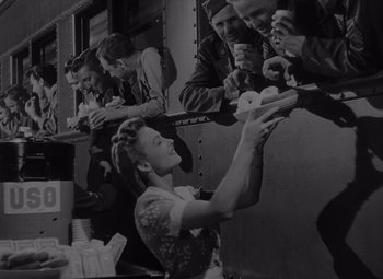 Movie still from “It's a Wonderful Life” (1946), directed by Frank Capra – A group of men and women eating donuts; Medium shot, High angle