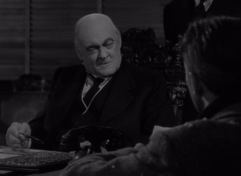 Movie still from “It's a Wonderful Life” (1946), directed by Frank Capra – An older man sitting at a table in a suit and tie; Close Up shot, Over the shoulder angle