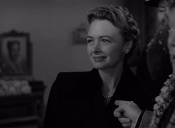 Movie still from “It's a Wonderful Life” (1946), directed by Frank Capra – An old photo of a woman in a black suit smiling; Close Up shot, Over the shoulder angle