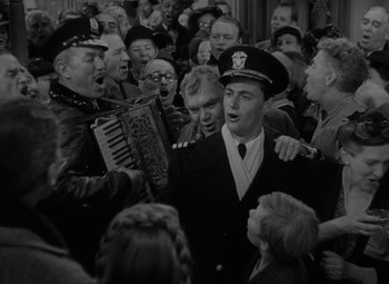 Movie still from “It's a Wonderful Life” (1946), directed by Frank Capra – A group of people that are standing around a man; Medium shot, High angle