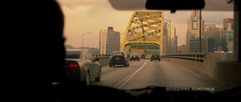 Movie still from “Jack Reacher” (2012), directed by Christopher McQuarrie – Cars driving on a highway with a bridge in the background; Extreme Wide shot, High angle