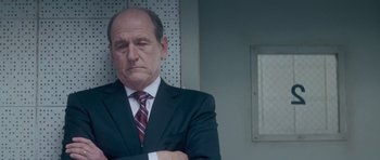 Movie still from “Jack Reacher” (2012), directed by Christopher McQuarrie – An older man wearing a suit and tie with his arms crossed; Close Up shot, Low angle