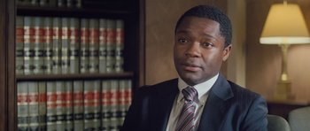 Movie still from “Jack Reacher” (2012), directed by Christopher McQuarrie – A man wearing a suit and tie in front of a book shelf; Close Up shot, High angle