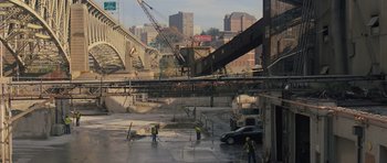 Movie still from “Jack Reacher” (2012), directed by Christopher McQuarrie – A group of men standing on top of a road next to a bridge; Extreme Wide shot, High angle