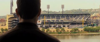 Movie still from “Jack Reacher” (2012), directed by Christopher McQuarrie – A man looking out over a river at a baseball stadium; Extreme Wide shot, Over the shoulder angle