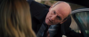 Movie still from “Jack Reacher” (2012), directed by Christopher McQuarrie – An older man wearing a suit and tie looking at the camera; Close Up shot, Over the shoulder angle