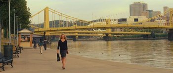 Movie still from “Jack Reacher” (2012), directed by Christopher McQuarrie – A woman in a black dress is walking by the water; Extreme Wide shot, Over the shoulder angle