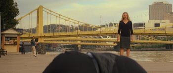 Movie still from “Jack Reacher” (2012), directed by Christopher McQuarrie – A woman in a black dress standing in front of a yellow bridge; Wide shot, Over the shoulder angle