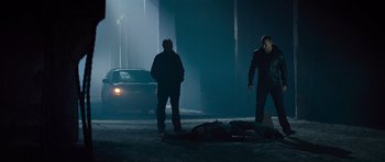 Movie still from “Jack Reacher” (2012), directed by Christopher McQuarrie – Two men standing next to a dead body in the dark; Wide shot, Over the shoulder angle