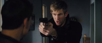 Movie still from “Jack Reacher” (2012), directed by Christopher McQuarrie – A man holding a gun in a room; Close Up shot, Over the shoulder angle