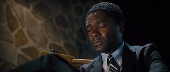 Movie still from “Jack Reacher” (2012), directed by Christopher McQuarrie – A man in a suit and tie sitting in front of a piano; Close Up shot, High angle