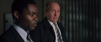 Movie still from “Jack Reacher” (2012), directed by Christopher McQuarrie – A man in a suit and tie next to another man in a suit and tie; Close Up shot, Over the shoulder angle