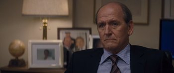 Movie still from “Jack Reacher” (2012), directed by Christopher McQuarrie – An older man wearing a suit and tie in a room; Close Up shot, Over the shoulder angle