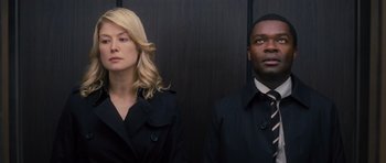 Movie still from “Jack Reacher” (2012), directed by Christopher McQuarrie – A woman and a man standing next to each other in front of a wall; Medium shot, Low angle