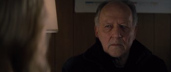 Movie still from “Jack Reacher” (2012), directed by Christopher McQuarrie – An older man in a black jacket is looking at the camera; Close Up shot, Over the shoulder angle