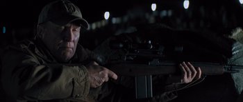 Movie still from “Jack Reacher” (2012), directed by Christopher McQuarrie – A man pointing to a rifle in a dark room; Close Up shot, Over the shoulder angle