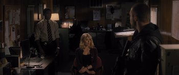 Movie still from “Jack Reacher” (2012), directed by Christopher McQuarrie – A woman sitting on a chair in a dark room; Medium shot, Over the shoulder angle