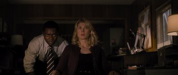 Movie still from “Jack Reacher” (2012), directed by Christopher McQuarrie – A woman standing next to a man in a dark room; Medium shot, Low angle