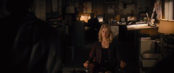 Movie still from “Jack Reacher” (2012), directed by Christopher McQuarrie – A woman sitting on a chair in a dark room; Medium shot, Over the shoulder angle