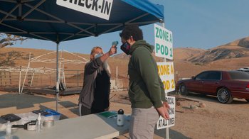 Movie still from “Jackass 4.5” (2022), directed by Jeff Tremaine – A man and a woman wearing face coverings at an outdoor event; Wide shot, Over the shoulder angle
