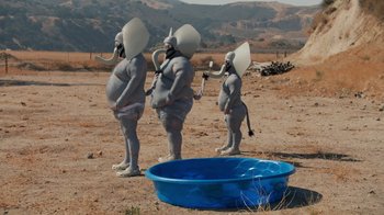 Movie still from “Jackass 4.5” (2022), directed by Jeff Tremaine – A group of people dressed as an elephant standing next to a blue tub; Extreme Wide shot, High angle