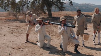 Movie still from “Jackass 4.5” (2022), directed by Jeff Tremaine – A group of men in suits and hats holding a baseball bat; Wide shot, High angle
