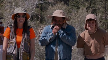 Movie still from “Jackass 4.5” (2022), directed by Jeff Tremaine – A group of people standing next to each other on top of a hill; Medium shot, Over the shoulder angle