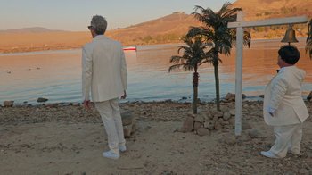Movie still from “Jackass 4.5” (2022), directed by Jeff Tremaine – A man in a white suit standing on the beach; Wide shot, Low angle