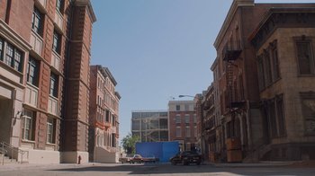 Movie still from “Jackass 4.5” (2022), directed by Jeff Tremaine – A truck driving down a street next to tall brick buildings; Extreme Wide shot, Low angle