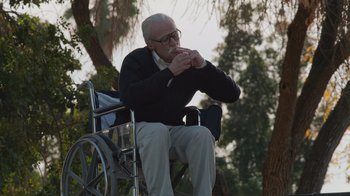 Movie still from “Jackass 4.5” (2022), directed by Jeff Tremaine – An older man sitting in a wheelchair eating a sandwich; Wide shot, Low angle